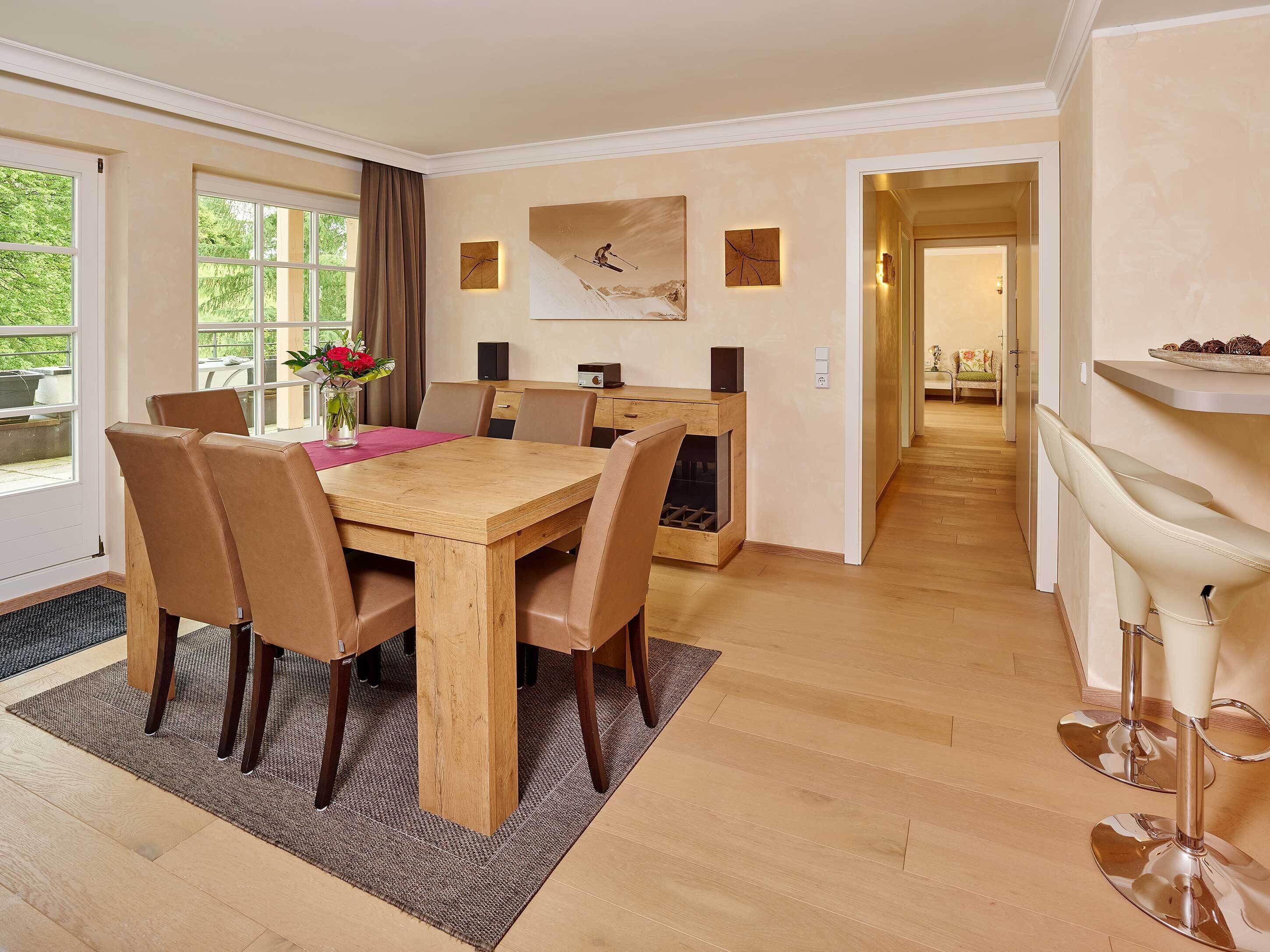 Een eetgedeelte met een houten tafel en stoelen, een bloevas en een schilderij aan de muur.