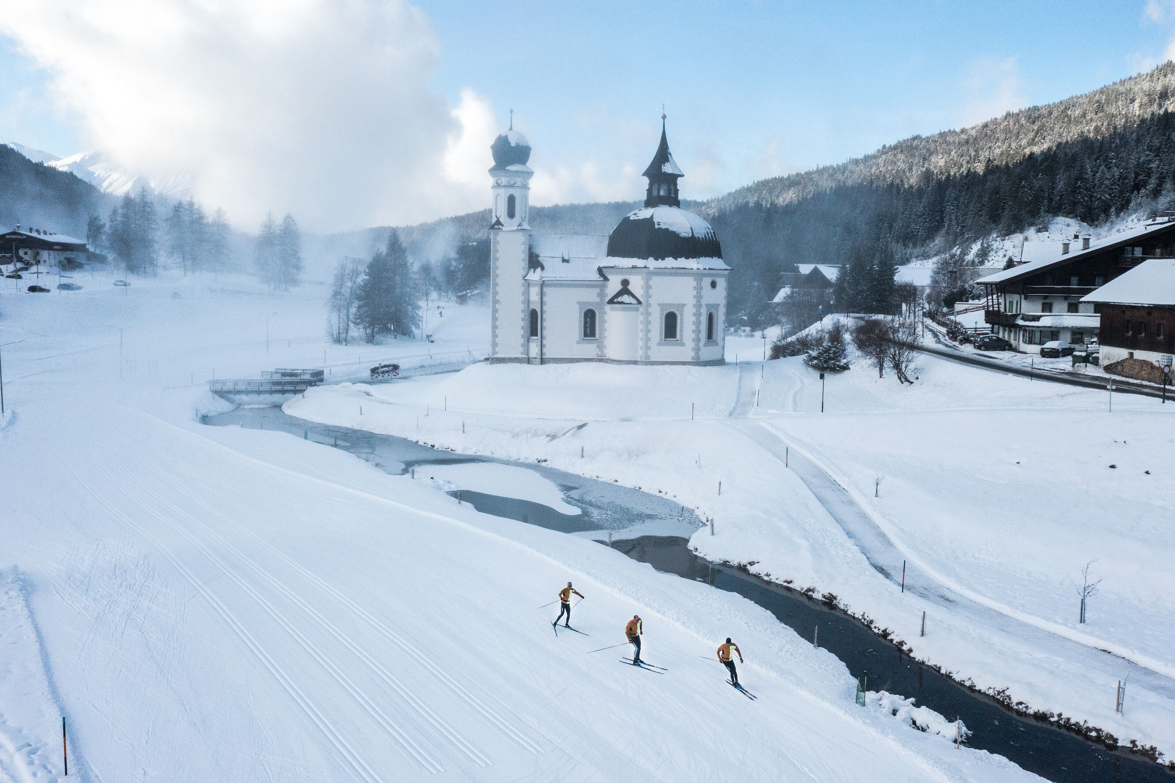 Paisaje nevado con una iglesia, un río y una pista de esquí.