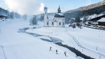 Paisaje nevado con una iglesia, un río y una pista de esquí.