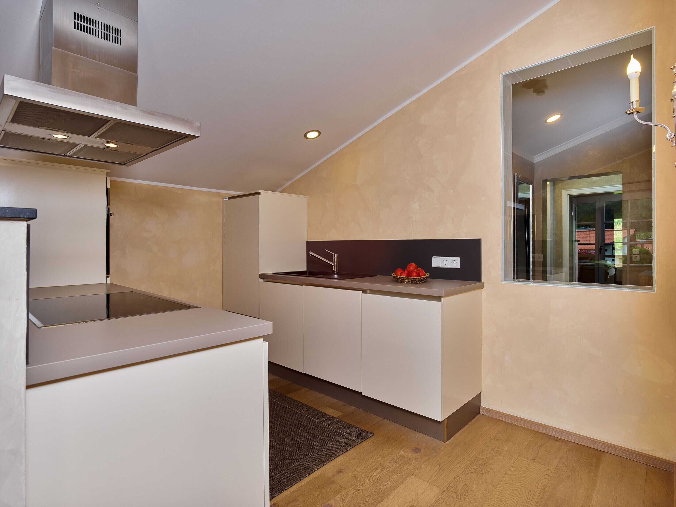 Una cocina compacta con estufa integrada, un lavamanos pequeño y una ventana con vistas.
