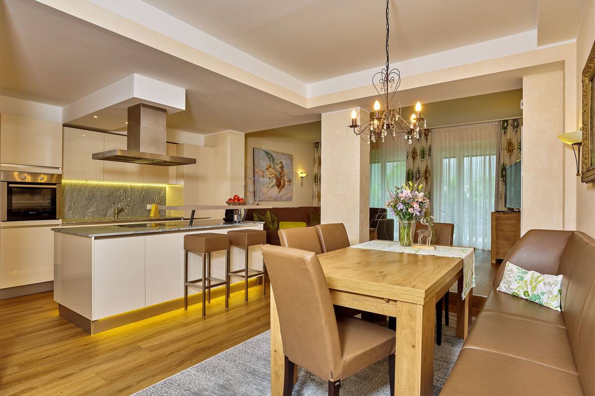 A modern kitchen with a central island, bar stools, and a dining area with a wooden table and chairs.
