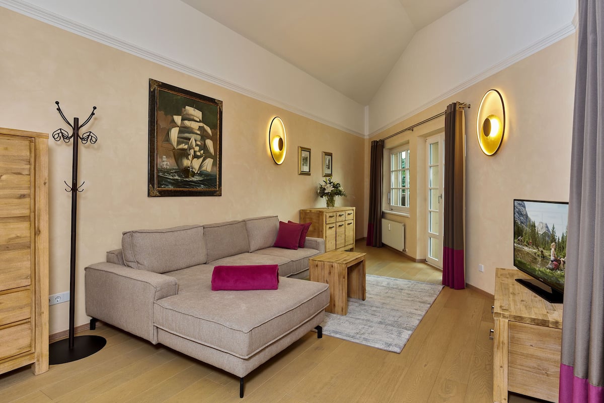 A modern living room with a sofa, a wooden cabinet, a coat rack, and a painting on the wall.
