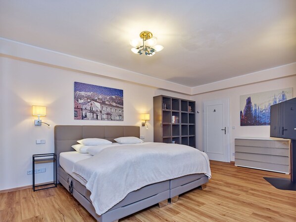 Un dormitorio moderno con una cama, lámparas de noche, una estantería y obras de arte en las paredes.