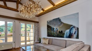 A modern living room with a glass coffee table, beige sofa, and a large painting of horses. - A-VITA Viktoria Residenzen (Seefeld in Tirol)
