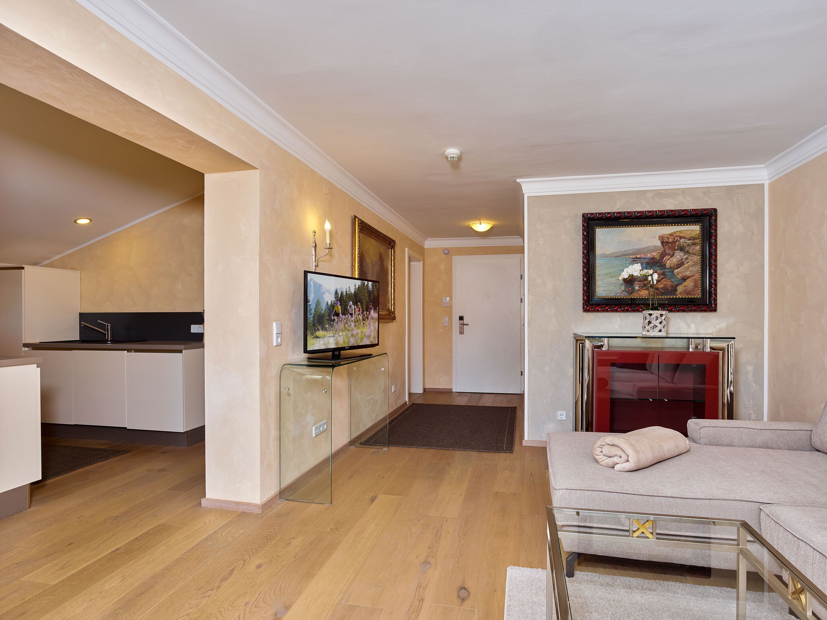 Uma sala de estar moderna com um sofá, uma mesa de centro de vidro e uma TV em um móvel.