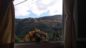 A room with a bed, a window with curtains, and a vase of flowers on the windowsill. - Aggelos House in Kalamitsi (Lefkada)