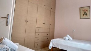 A small, neatly arranged room with a wooden wardrobe, a bed, and a bedside table. - Aggelos House in Kalamitsi (Lefkada)