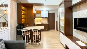 A compact living space with a kitchen, dining area, and a TV mounted on a wall. - Great Choice And Modern 2Br At Transpark Juanda Bekasi Timur Apartment (Bekasi)