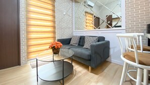 A modern living room with a grey sofa, a round glass coffee table, and a white chair. - Great Choice And Modern 2Br At Transpark Juanda Bekasi Timur Apartment (Bekasi)
