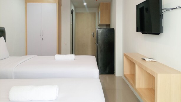 Una habitación de hotel con dos camas, televisor, refrigerador y un armario de madera.