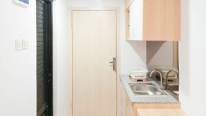 Cocina compacta con puerta de madera, encimera con un lavabo y un mueble pequeño encima.