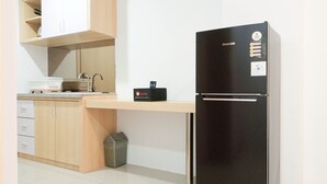 Una cocina moderna con un refrigerador negro, armarios de madera, una encimera y un cubo de basura.