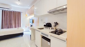 A modern kitchen with a built-in stove, a dish rack, and a small refrigerator. - Relaxing Studio At Sky House Alam Sutera Apartment (Tangerang)