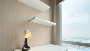 A modern room with a white desk, a lamp, and a view of a port through a large window.