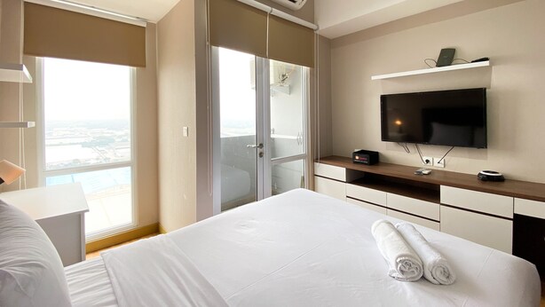 A hotel room with a bed, a TV, a desk, and a view of the city.