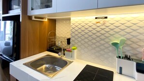 A modern kitchen with a stainless steel sink, a dish rack, and a wall-mounted utensil holder.