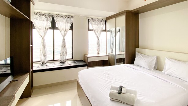 Habitación de hotel con una cama grande, una mesita de noche, un espejo y una ventana con cortinas.