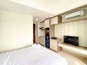 Et hotelværelse med seng, fjernsyn, minibar og integreret tekøkken.