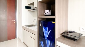 Una cocina con nevera, microondas y cafetera sobre la encimera.
