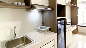 Una cocina moderna con un lavamanos de acero inoxidable, armarios blancos y una campana extractora empotrada.