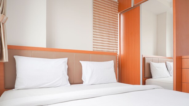 A hotel room with a bed, a wooden headboard, and a mirror. - Comfort And Good Choice 2Br Signature Park Grande Apartment (Jakarta)
