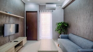 A modern living room with a TV, sofa, and a coffee table. - Elegant And Comfy 2Br At Transpark Cibubur Apartment (Depok)