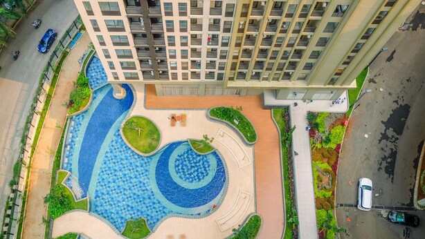 A high-rise building with a rooftop pool featuring a spiral design, surrounded by greenery and a few seating areas. - Elegant And Comfy 2Br At Transpark Cibubur Apartment (Depok)