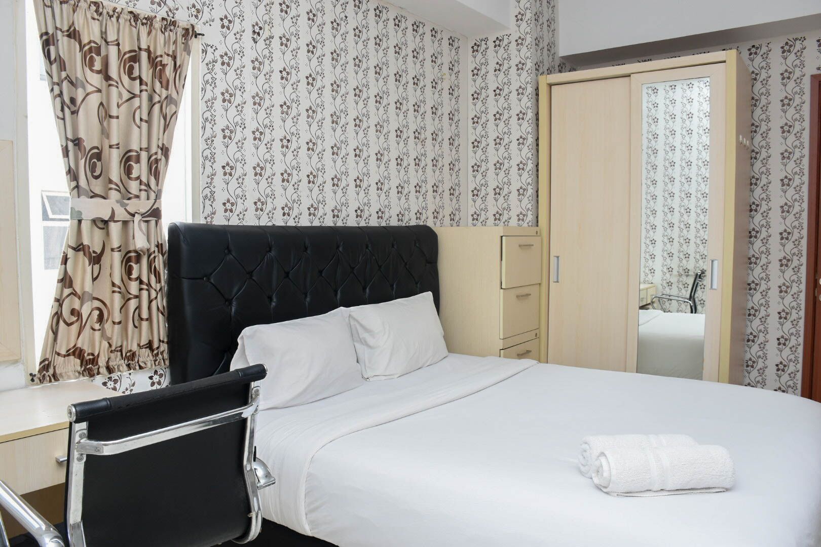 Une chambre d’hôtel avec un lit, une chaise, un bureau et une armoire.