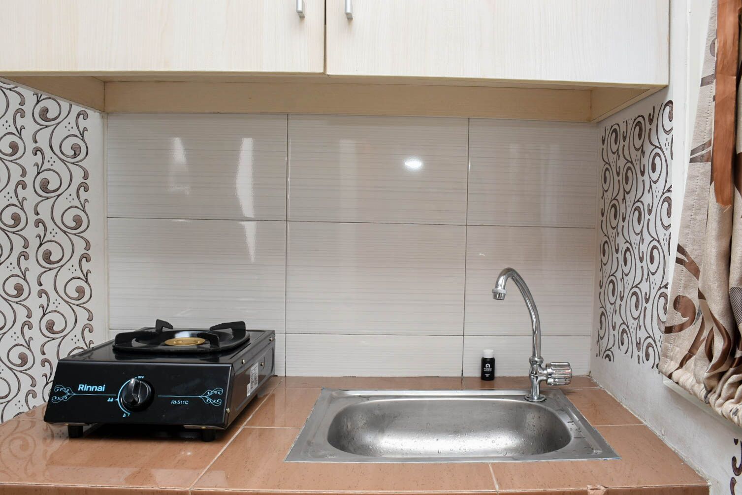 A kitchen with a gas stove, sink, and patterned tiles.