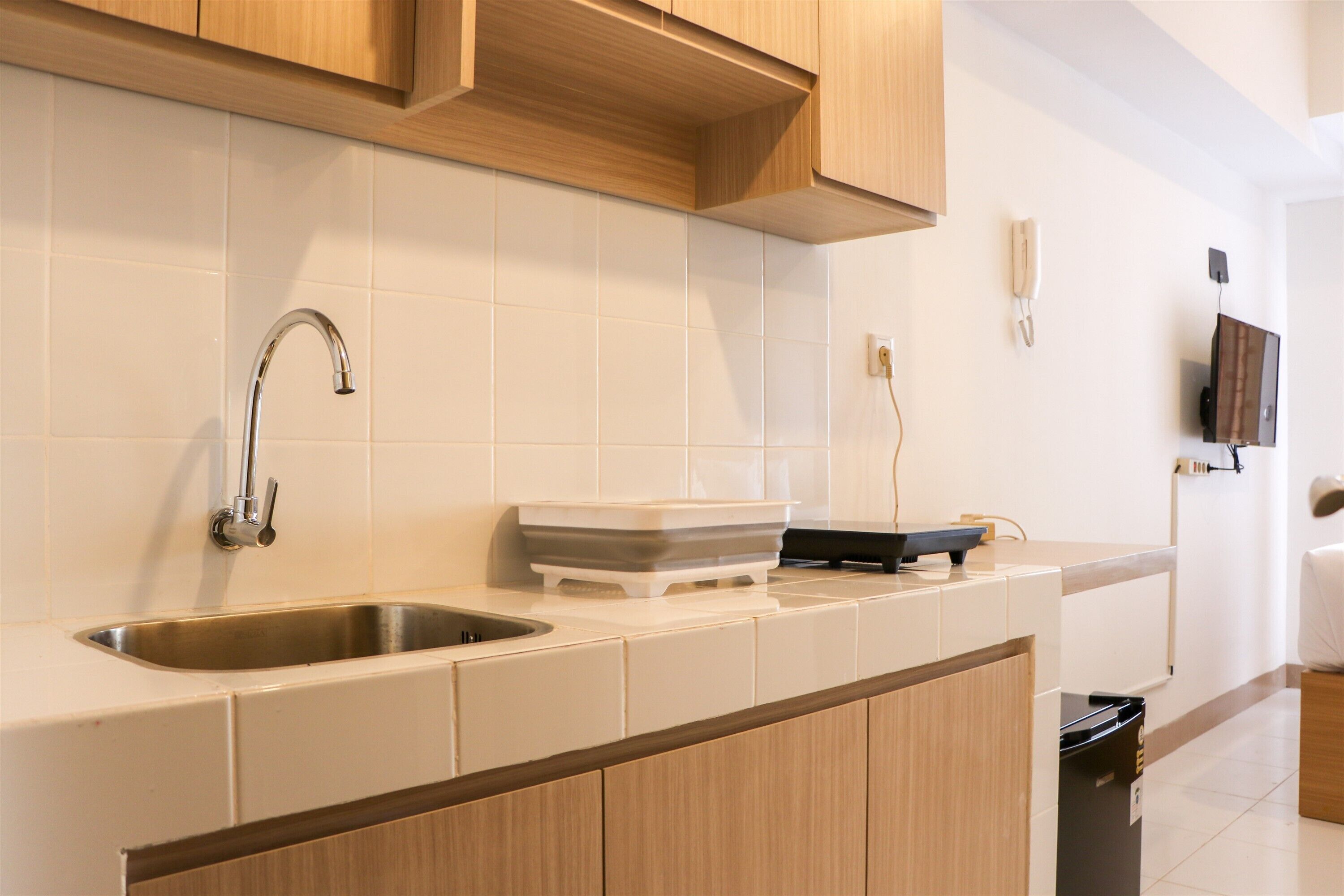Una cocina moderna con un lavamanos de acero inoxidable, armarios de madera y salpicadero de azulejos.