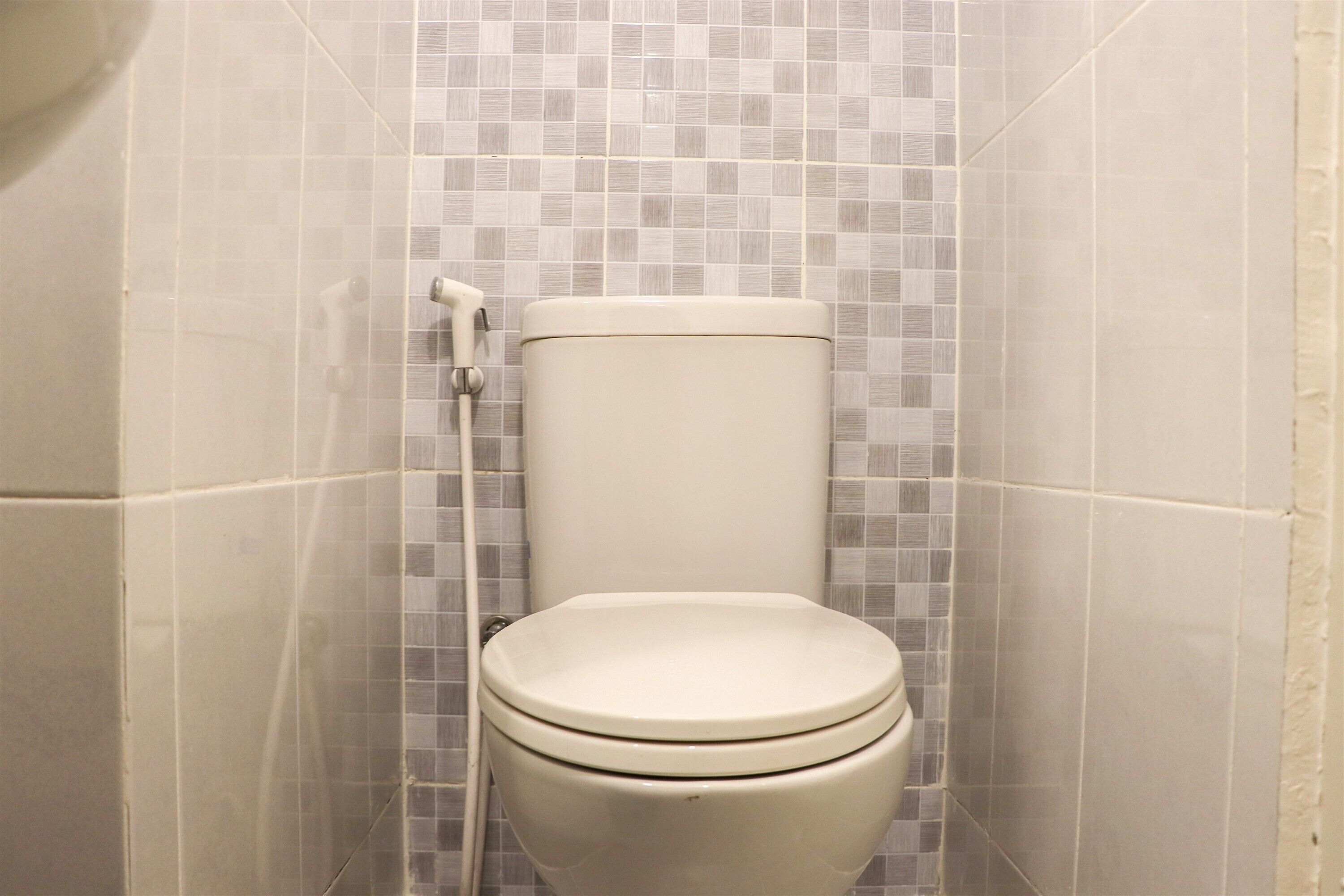 Un inodoro en un baño con paredes de azulejos.