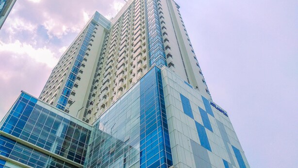 A high-rise building with multiple floors, featuring a mix of glass and concrete facades. - Minimalist And Nice Studio Apartment Atlanta Residence (Depok)