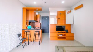 A compact living space with a kitchenette, a dining area, and a seating area with a TV. - Minimalist And Nice Studio Apartment Atlanta Residence (Depok)
