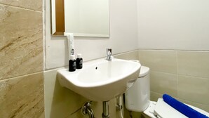 Een badkamer met een wit wastafelmeubel, een spiegel en toiletartikelen.