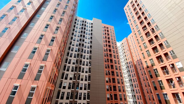 Een hoog gebouw met meerdere verdiepingen, met een modern architectonisch ontwerp in een combinatie van roze en beige tinten.