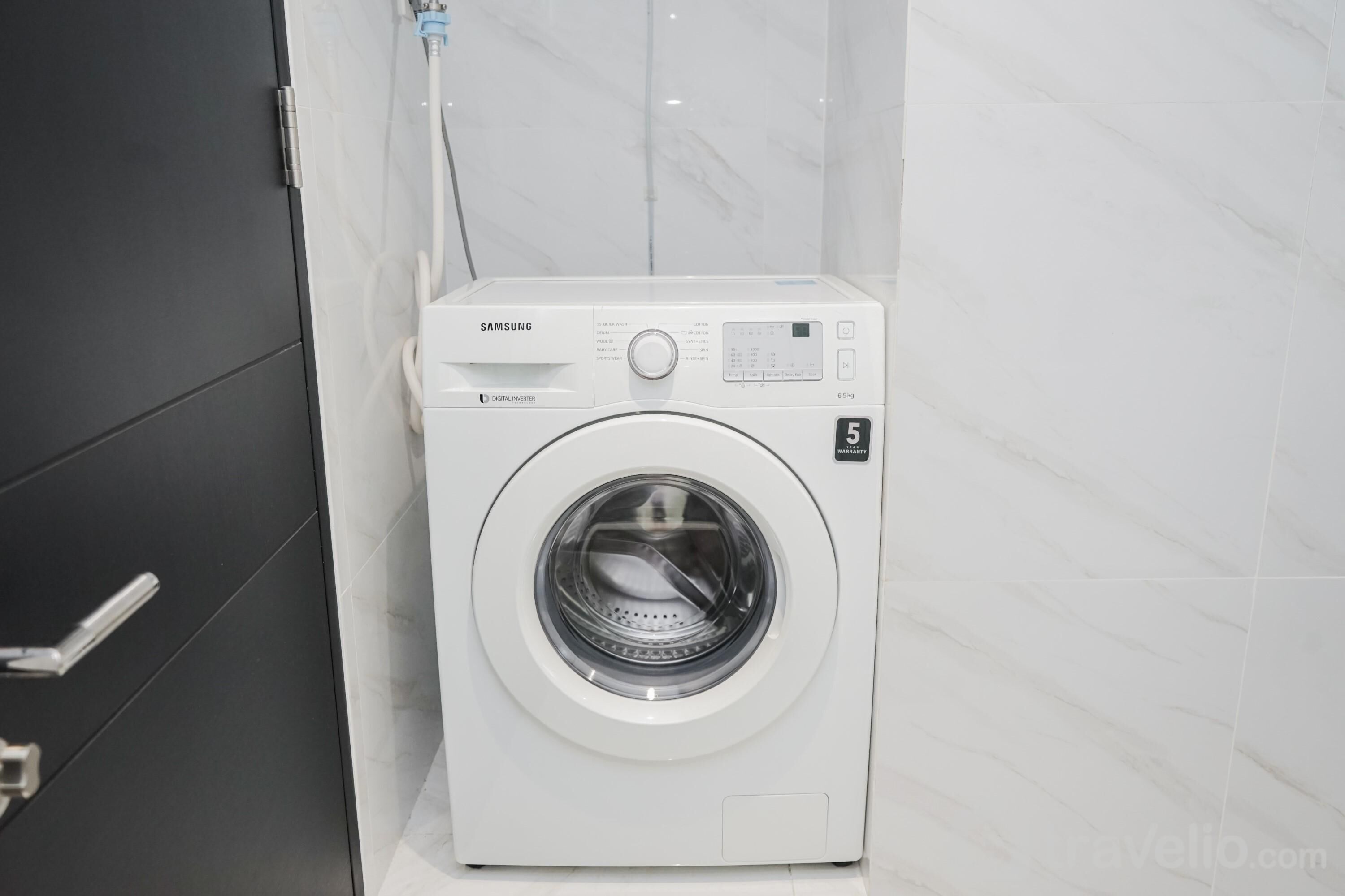 A Samsung digital washer in a bathroom with white marble tiles.