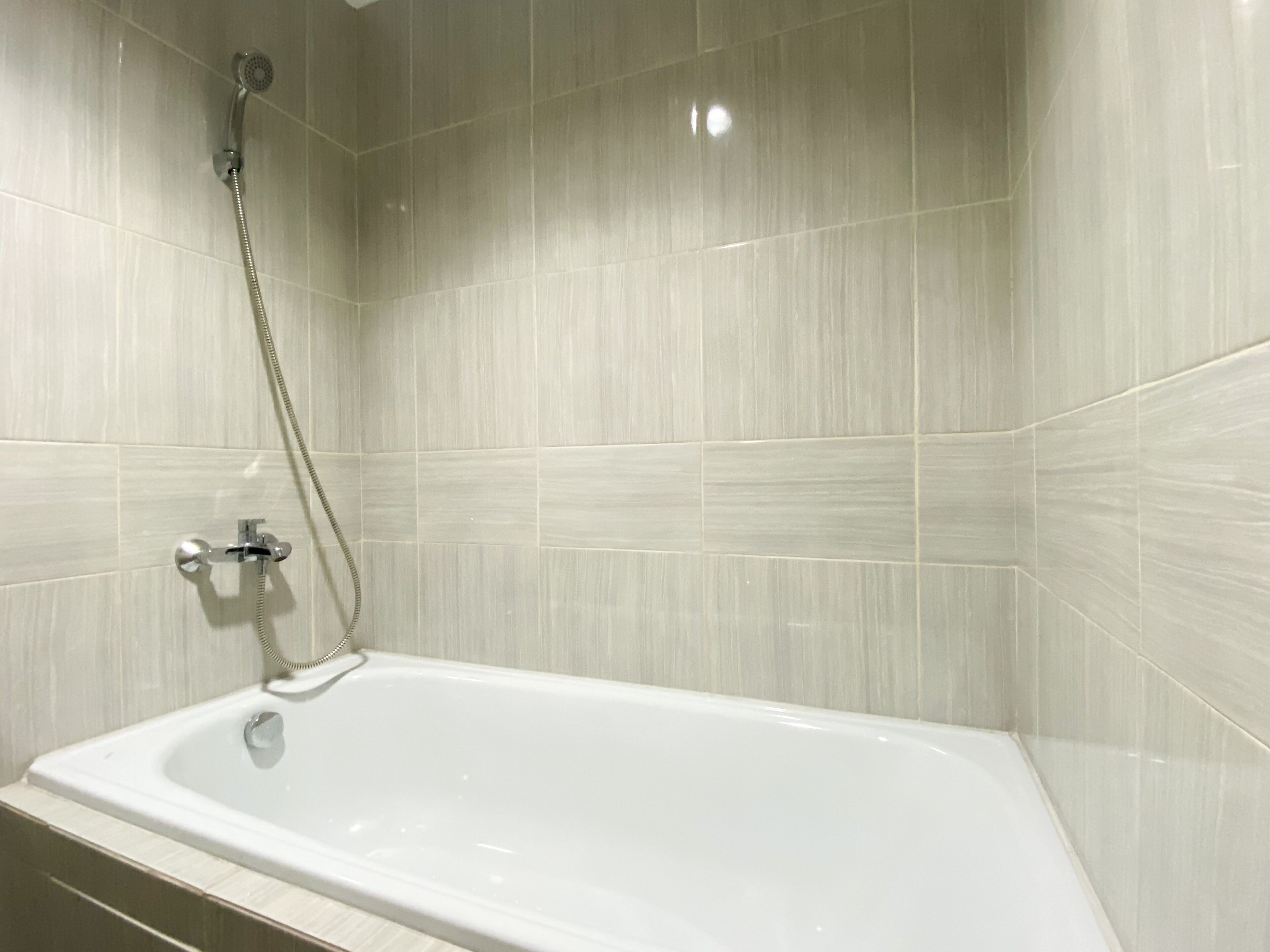 Une salle de bain avec une baignoire blanche, une pomme de douche et un robinet.