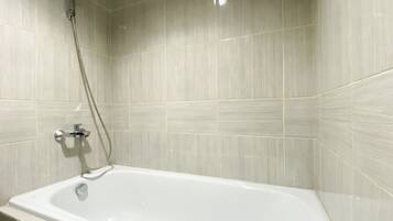 Une salle de bain avec une baignoire blanche, une pomme de douche et un robinet.
