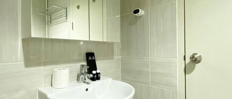 Une salle de bain avec un lavabo blanc, un miroir et des toilettes.