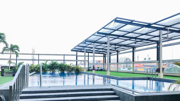 Ein Dachpool mit klarem, blauem Wasser, umgeben von einer Glaskonstruktion und Treppen, die zum Pool führen.