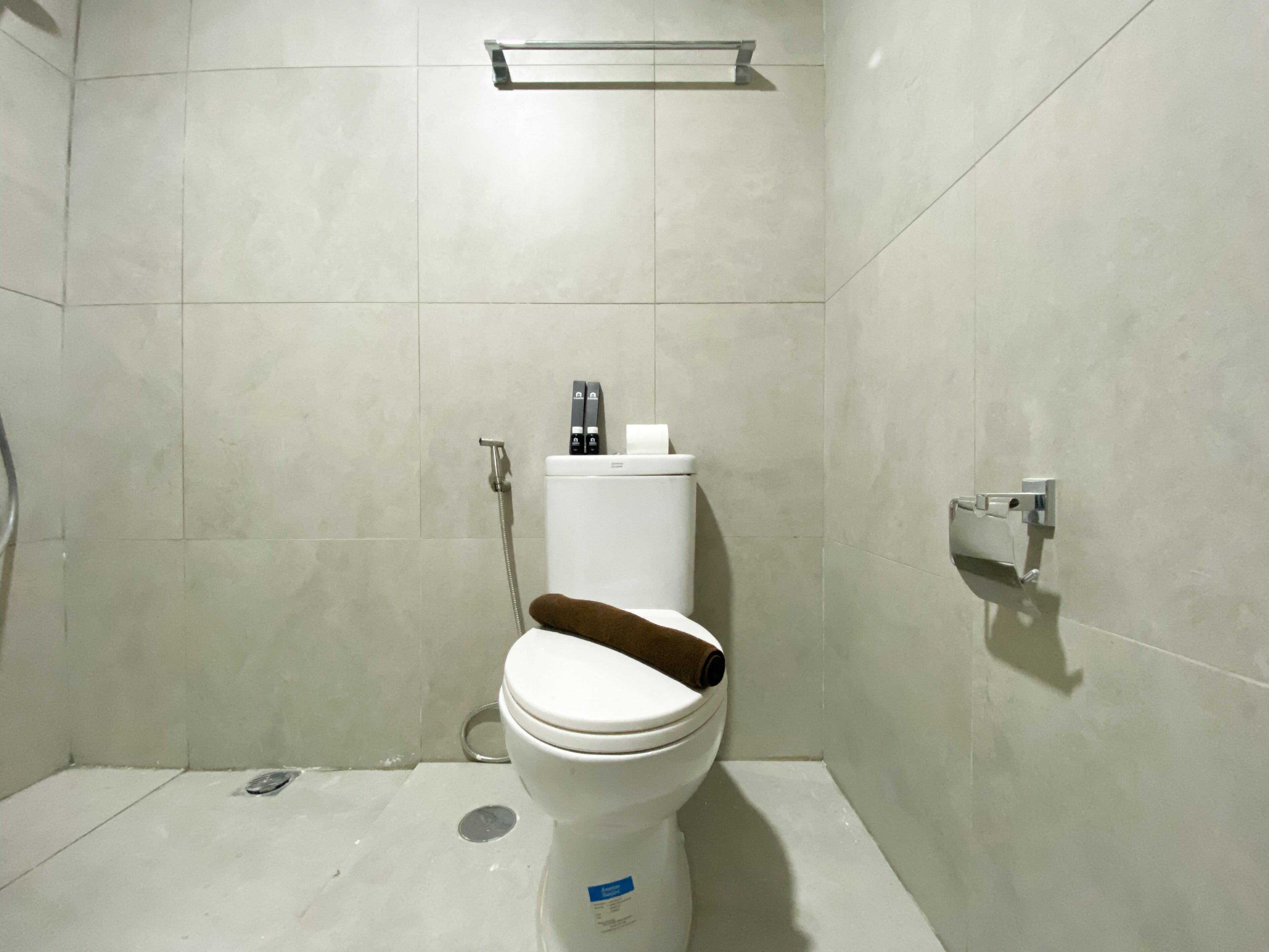 Een badkamer met toilet, douche en toiletrolhouder.
