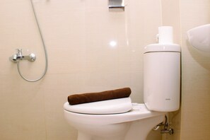 A bathroom with a toilet, towel, and showerhead.