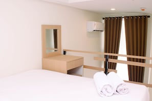 Relax in a serene space with a neatly made bed, wooden headboard, and wall-mounted air conditioning unit.