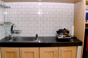 Kitchen features a stainless steel sink, black electric stove, and electric kettle.