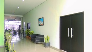A clean, modern lobby with a black reception desk, potted plants, and a large black door.