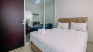 A hotel room with a bed, a glass door, and a view of the outside.