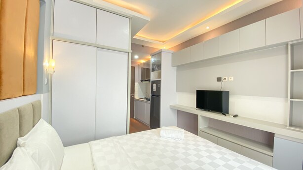 Une chambre d’hôtel avec un lit, un téléviseur posé sur une étagère et une armoire.