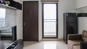 A modern kitchen with a marble countertop, a built-in TV, a refrigerator, and a door leading to a balcony. - Comfort And Cozy Stay 2Br At 29Th Floor Transpark Cibubur Apartment (Depok)