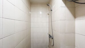 A small, tiled shower stall with a handheld showerhead and a fixed showerhead on the wall. - Compact Studio Room Apartment Vida View Makassar (Makassar)