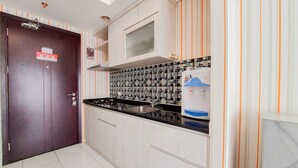 Eine Küche mit weißen Schränken, einer schwarzen Arbeitsplatte, einer Edelstahlspüle, einer gefliesten Rückwand und einem Wasserspender.